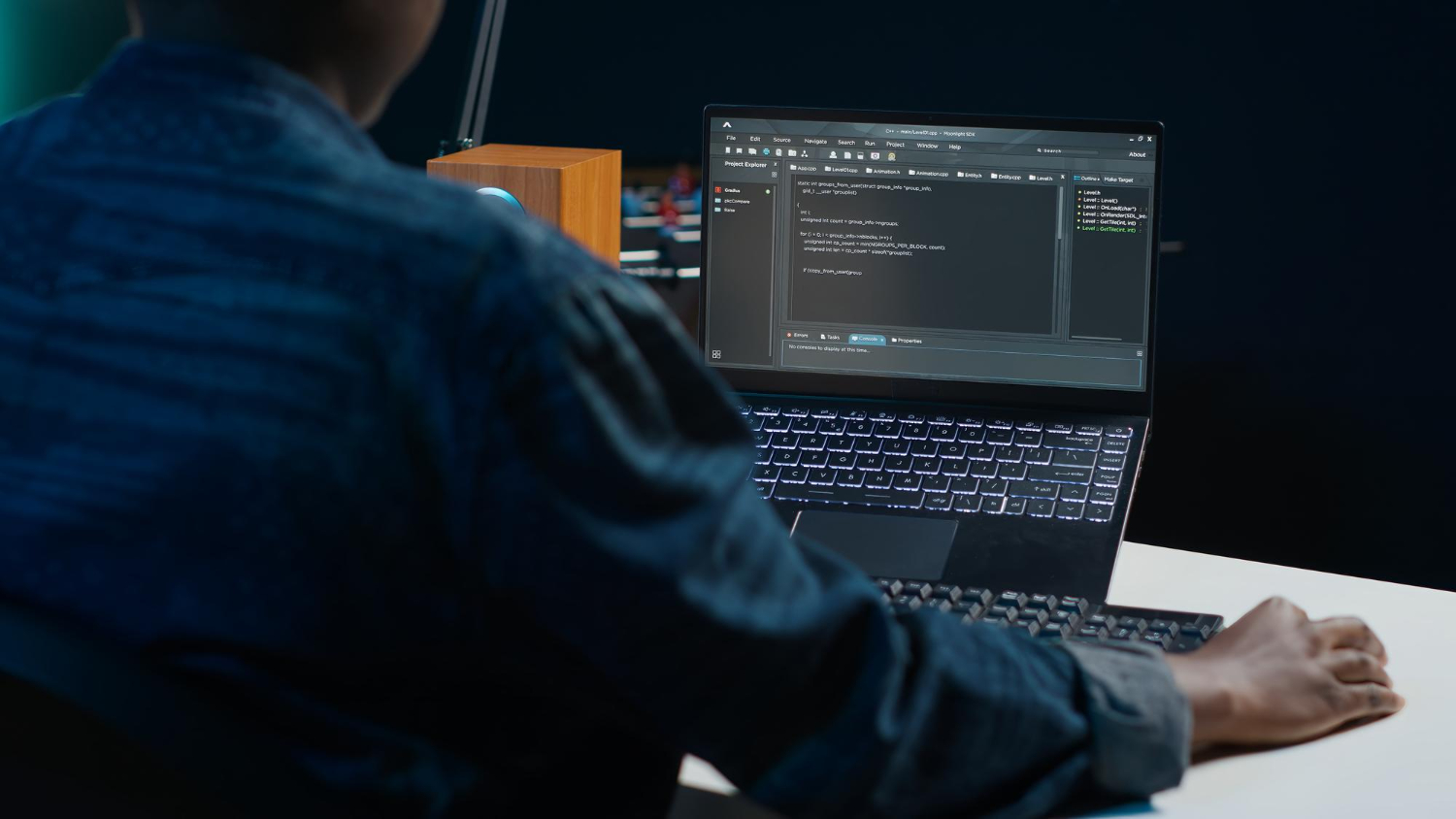 Developer coding on laptop with dark theme showing implementation work